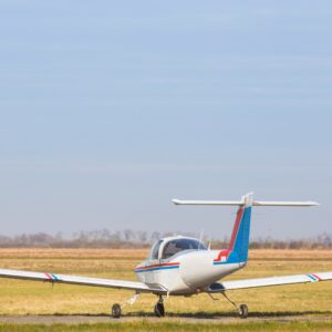 A small white glider airplane on a grassy field under a clear sky.